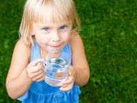 Billede af en lille pige med et glas vand i hånden